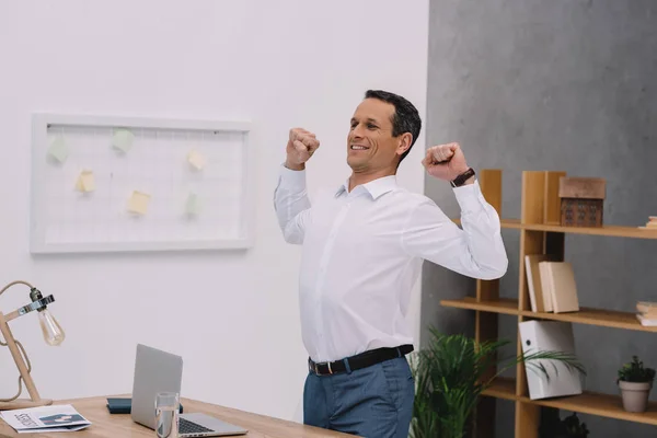 Handsome mature businessman stretching at his workplace in office — Stock Photo