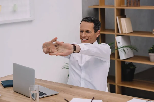 Красивый зрелый бизнесмен протягивает руки в офисе — стоковое фото