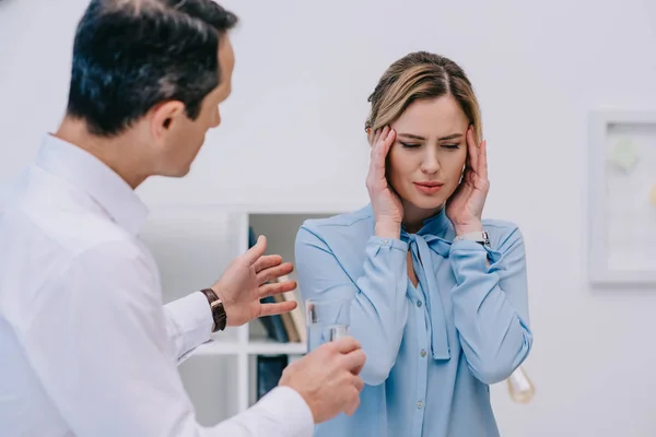 Donna d'affari ha mal di testa mentre il suo collega cerca di aiutarla in ufficio — Foto stock