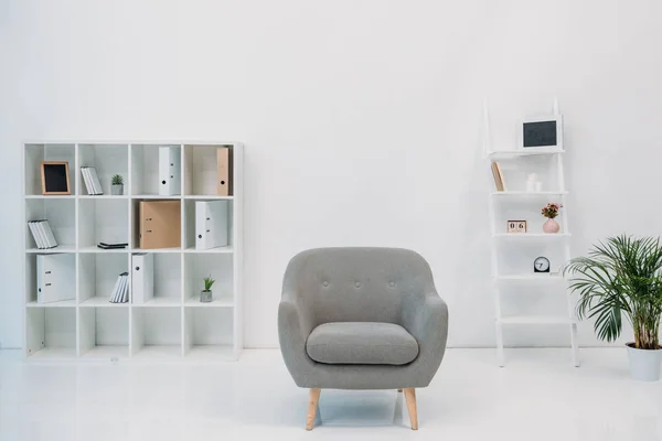 Moderne Büroeinrichtung mit grauem Sessel und Ordnern in den Regalen — Stockfoto
