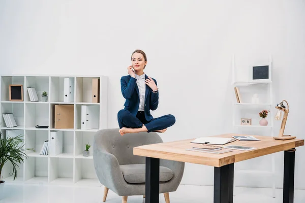 Bela jovem empresária falando por smartphone enquanto levita no local de trabalho — Fotografia de Stock