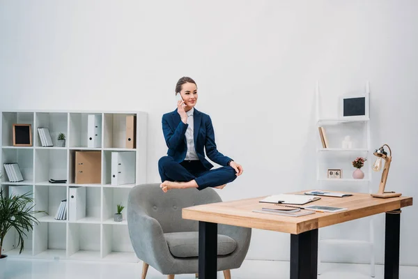 Business woman talking by smartphone while levitating at workplace — стоковое фото