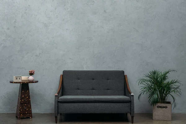 Aconchegante sofá vazio e calendário na mesa e planta de sala verde perto da parede cinza — Fotografia de Stock