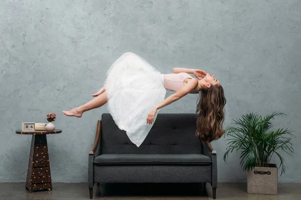 Bela jovem descalça mulher levitando acima sofá — Fotografia de Stock