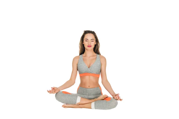 Young woman with closed eyes meditating in lotus position isolated on white — Stock Photo