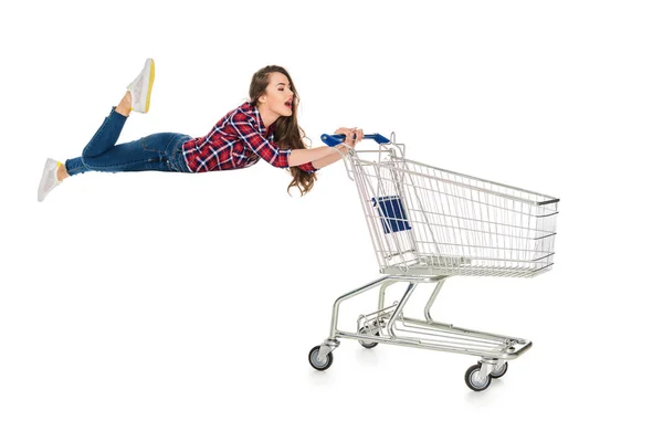 Молодая женщина левитации с пустыми магазинами тележки изолированы на белом — стоковое фото