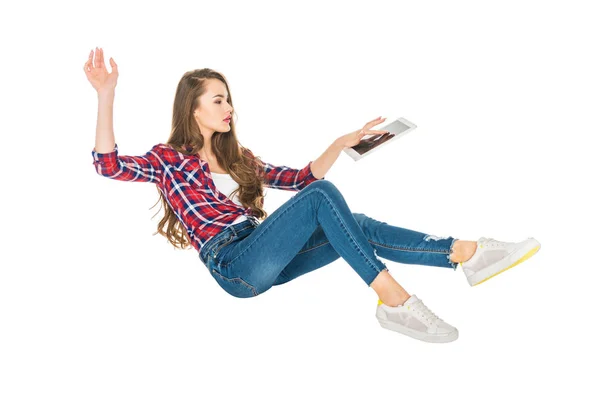 Mujer joven usando tableta digital mientras levita aislada en blanco - foto de stock