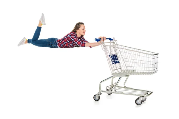 Happy young woman levitating with empty shopping trolley isolated on white — Stock Photo