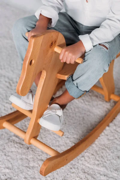 Cropped image of african american kid sitting on rocking horse — Stock Photo