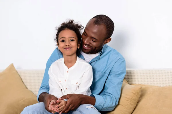 Feliz pai e filha afro-americanos no sofá em casa — Fotografia de Stock
