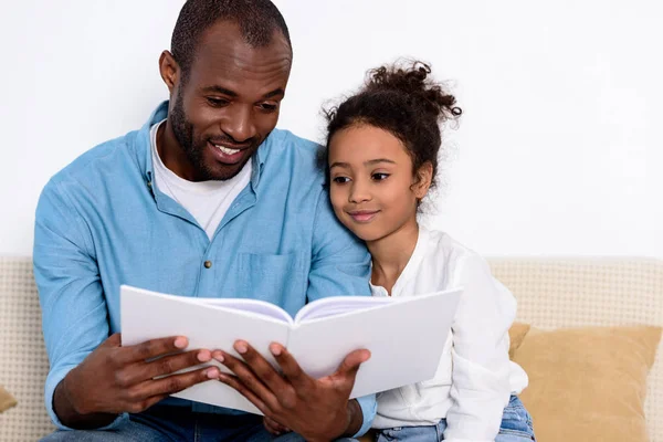 Feliz afroamericano padre lectura libro a hija — Stock Photo