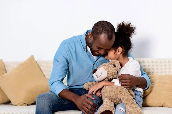 Père afro-américain étreignant fille avec ours en peluche — Photo de stock