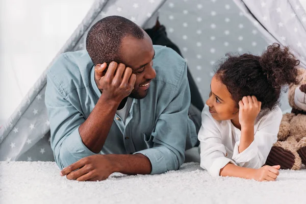 Afrikanisch-amerikanischer Vater und Tochter liegen auf dem Boden und schauen sich zu Hause an — Stockfoto