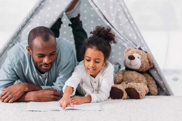 Afro-américain père et fille lecture livre ensemble à la maison — Photo de stock