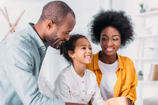 Sonrientes afroamericanos padres e hija divirtiéndose en casa - foto de stock