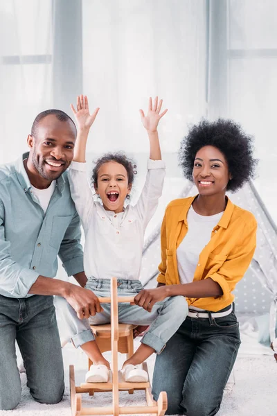 Afro-americanos pais e filha brincando com cavalo de balanço em casa — Fotografia de Stock