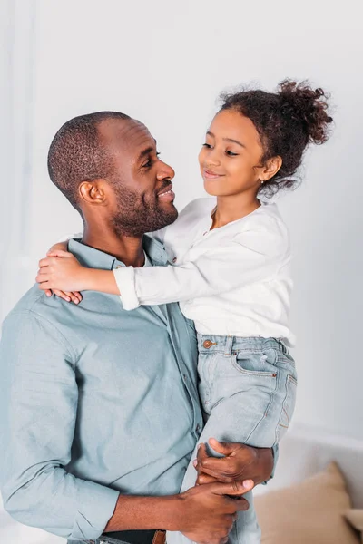 Africano americano padre llevar y abrazar hija en casa - foto de stock