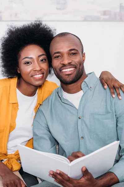 Lächelnd afrikanisches amerikanisches Paar, das sich umarmt und zu Hause in die Kamera schaut — Stockfoto