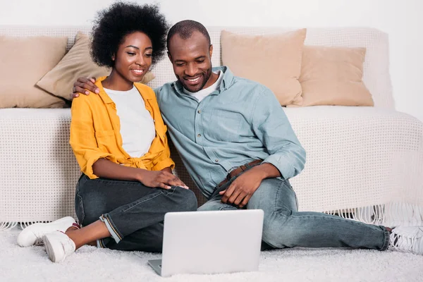 Lächelndes afrikanisch-amerikanisches Paar schaut sich Film auf Laptop zu Hause an — Stockfoto