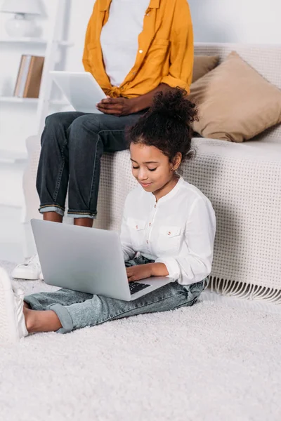 Cropped image of african american mother and daughter using tablet and laptop at home — Stock Photo