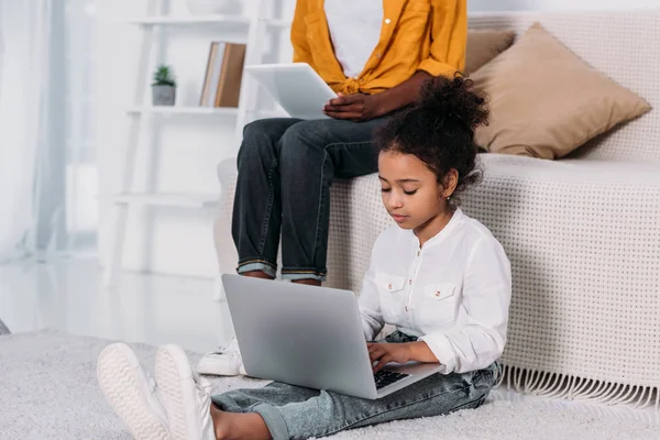 Cropped image of african american mother and daughter using tablet and laptop — Stock Photo