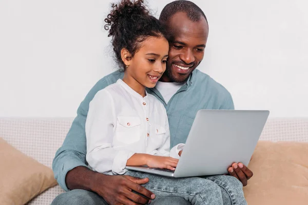 Happy african american father and daughter using laptop at home — Stock Photo