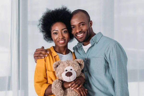 Happy african american couple with teddy bear at home — Stock Photo