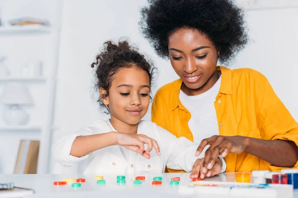 Madre afroamericana enseñando números de hija en casa - foto de stock