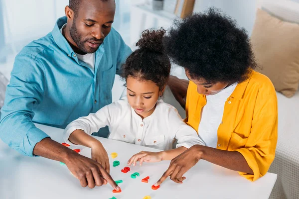 Africanos americanos padres enseñanza hija matemáticas en casa - foto de stock