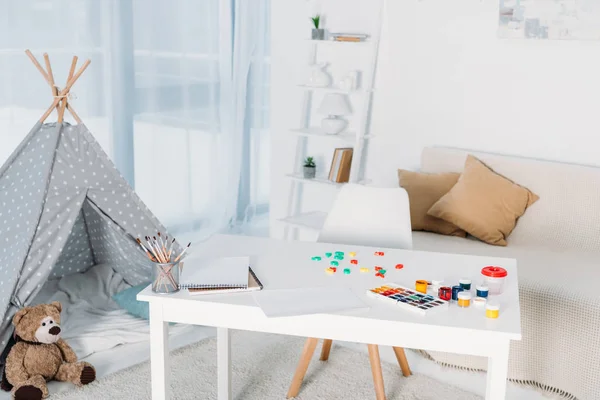 Poster paints and watercolor paints on table in room — Stock Photo