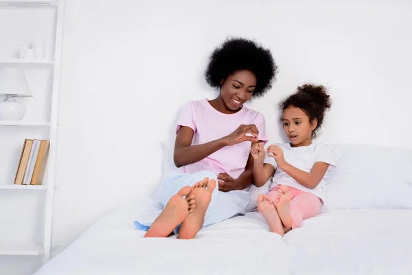 Afro-americana mãe e filha brincando na cama em casa — Fotografia de Stock