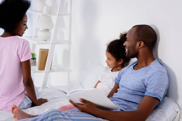 Afro-américains parents et fille qui se regardent dans le lit à la maison — Photo de stock