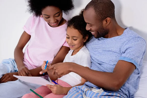 Afroamericanos padres ayudar hija pintura en álbum en casa — Stock Photo