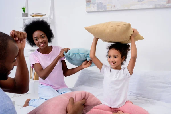 African american parents and daughter playing with pillows at home — Stock Photo