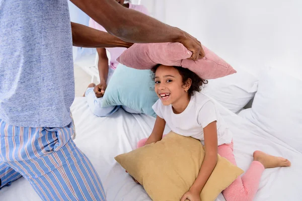 Image recadrée de parents afro-américains et leur fille jouant avec des oreillers à la maison — Photo de stock