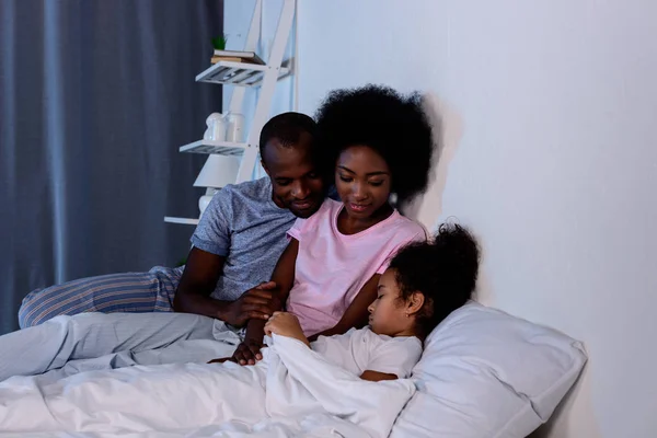 African american parents looking at sleeping daughter — Stock Photo