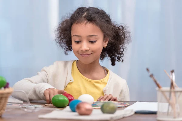 Чарівна афроамериканська дитина грає з розфарбованими великодніми яйцями — стокове фото
