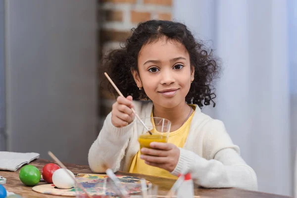 Bambino afroamericano mettere pennello in vetro con vernice per la pittura uova di Pasqua — Foto stock