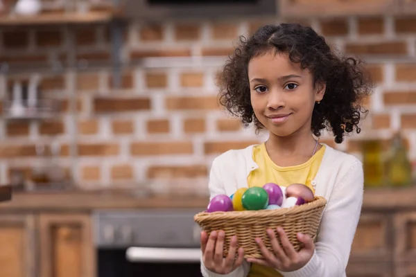 Adorable african american kid holding straw basket with painted easter eggs — Stock Photo