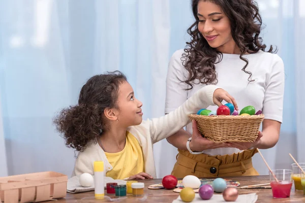 Afrikanisch-amerikanische Tochter holt bemaltes Osterei aus Strohkorb — Stockfoto