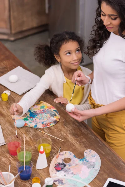 High angle view of african american mother and daughter painting together easter eggs — Stock Photo