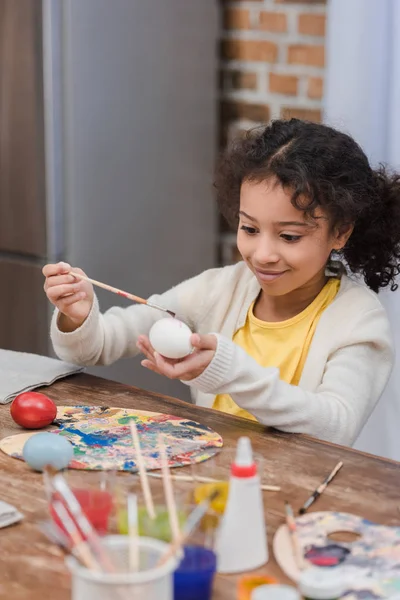 Niño afroamericano pintando huevos de Pascua - foto de stock