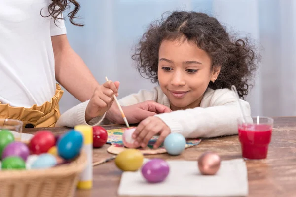 Imagem recortada de mãe e filha afro-americana pintando ovos de páscoa — Fotografia de Stock