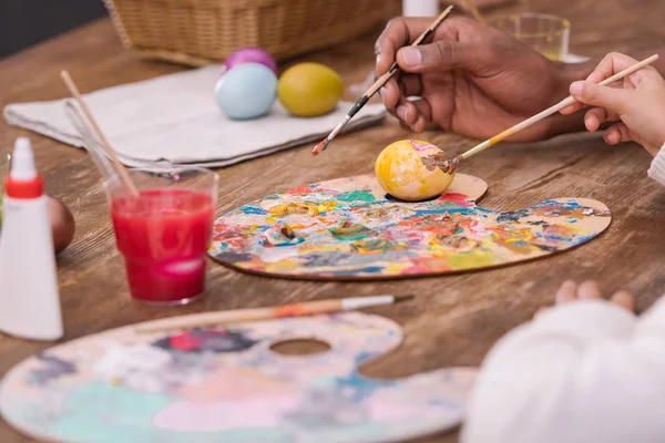 Imagem recortada de pai e filha afro-americanos pintando ovos de páscoa — Fotografia de Stock