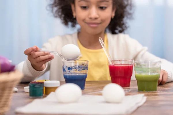 Bambino afroamericano che dipinge uova di Pasqua in bicchieri con vernici — Foto stock