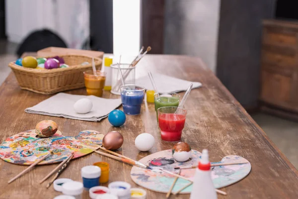 Oeufs peints avec peintures et brosses sur table en bois, concept de Pâques — Photo de stock