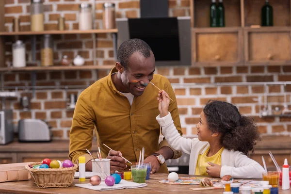 African american father and daughter having fun and painting faces, easter concept — Stock Photo