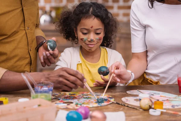 Image recadrée de parents afro-américains et de leur fille peignant des œufs de Pâques — Photo de stock