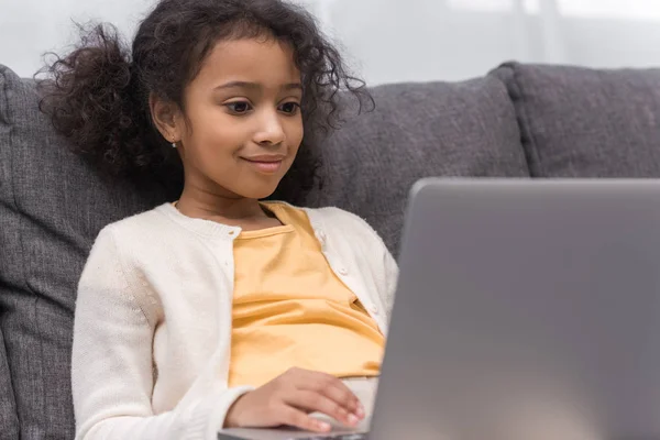 African american kid using laptop on sofa at home — Stock Photo