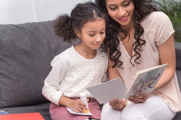 Happy african american mother and daughter looking at greeting cards on mothers day at home — Stock Photo